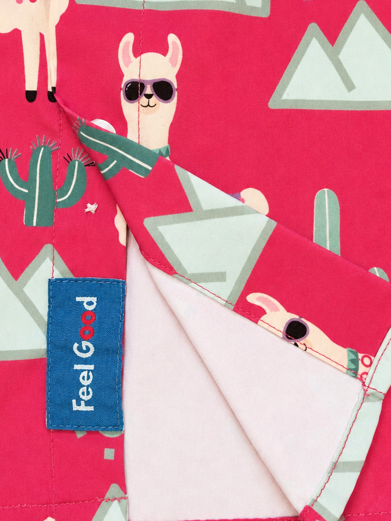 The Feel GOOD Tag on the Pink Llama shirt, featuring a cartoon llama print with sunglasses, cacti, and mountains. 